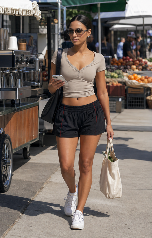 Red Monté khaki button V-neck crop top styled with black athletic shorts at a sunny city market