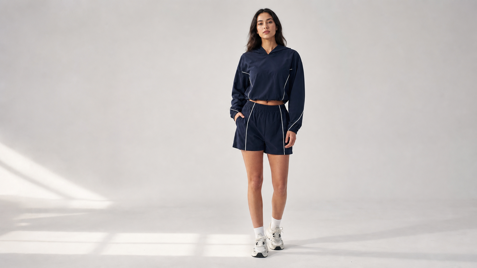Woman wearing Red Monté navy activewear with a hooded jacket and athletic shorts